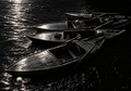 Empty wooden boats and a floating lotus in deep black shadows with brilliant silver moonlight, signed Dr. E.